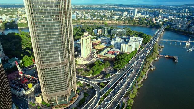Aerial footage of a modern urban landscape featuring glass skyscrapers, a high-speed highway, and a scenic city riverfront. Captured in Brisbane, Australia