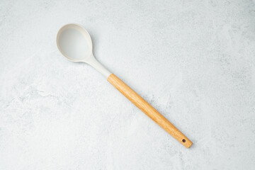 Wooden handle spoon placed on a light gray surface with minimalistic design