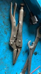 A set of metal tools on a blue surface, including a wrench and pliers, ideal for industrial and repair contexts.
