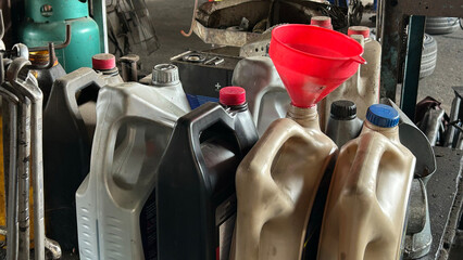 A collection of used oil containers with a funnel in an industrial setting, showcasing recycling...