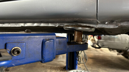 Close-up of a car on a hydraulic lift in an automotive repair shop, highlighting vehicle maintenance.