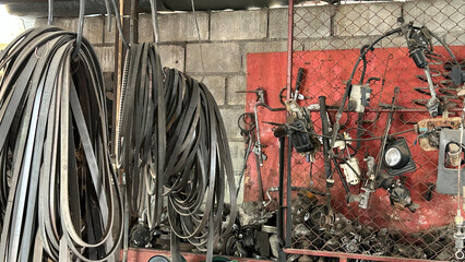 Collection of industrial belts and gears against a rustic workshop wall, showcasing mechanical...