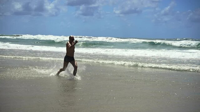 A hilarious middle-aged office escapee runs joyfully through ocean waves, his carefree sprint along a vast sandy beach under blue skies symbolizing the perfect break from routine.
