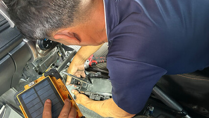 Technician repairing electronic device with tools; focused on precision and intricate components.