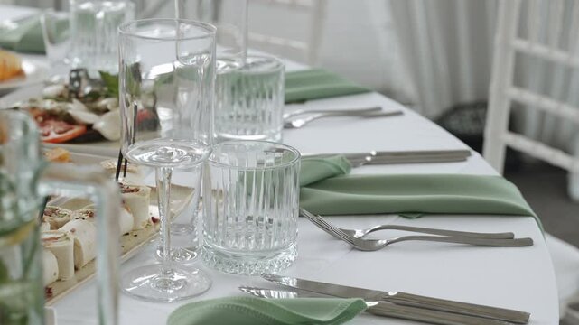 Served round table in restaurant with snacks, napkins and glasses. Background video of review of bright banquet hall without people before gala reception in daylight.
