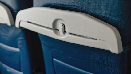 Airplane seat back with a white armrest and coat hanger