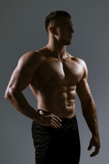 Fototapeta premium A Muscular Male Model captured in a Profile Pose with Dramatic HighContrast Lighting
