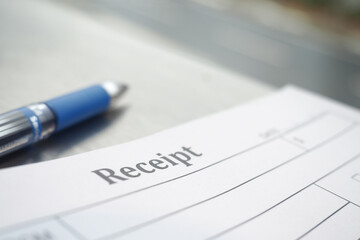 Receipt on a desk with a blue pen nearby during daytime