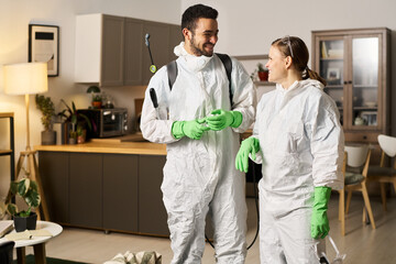 Obraz premium Colleagues in protective suits and gloves working in team in apartment