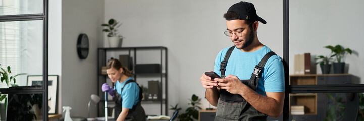 Header with worker using smartphone during cleaning