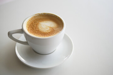 Creamy latte served in a white cup on a plate