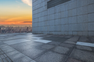 Fototapeta premium Empty square floor and brick wall with city skyline at sunset