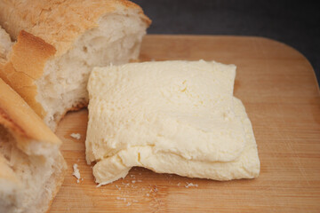 Fresh bread and creamy cheese on a wooden cutting board