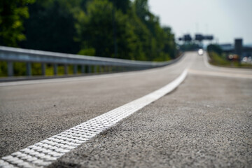 White rumble strip with 3D texture along road marking on extended highway ramp under construction