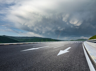 Fototapeta premium Asphalt road and green mountain with dramatic sky clouds nature landscape in summer
