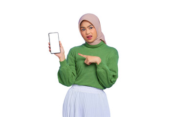 Confused beautiful Asian woman in green sweater and hijab pointing fingers at blank screen mobile phone isolated on transparent background