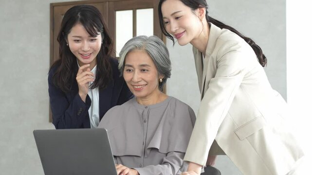 パソコンを見ながら話す3人のビジネスウーマン