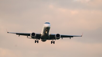 Majestic airplane descends gracefully through soft clouds at golden hour before landing on the runway