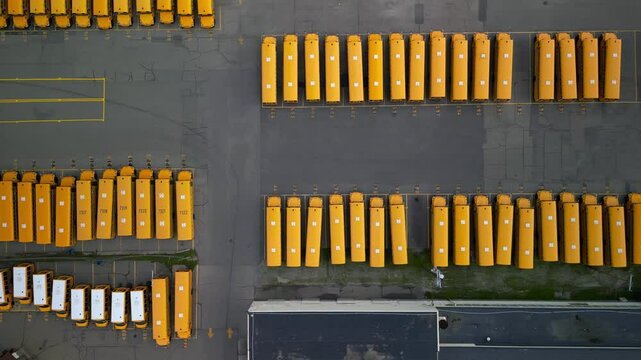 Top down view of rows of school buses in open garage storage yard during school holiday time