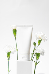white cosmetic tube on a white background on white cube. The concept of a cream with natural ingredient and not testing on animals.