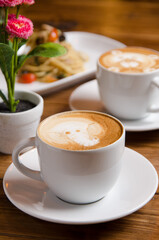 two cups of cappuccio coffee, each with different latte art