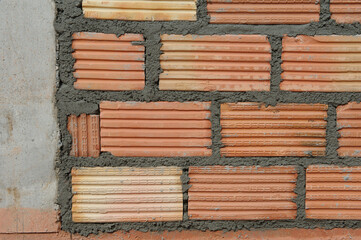 Red brick blocks are built with hands and tools on the building.