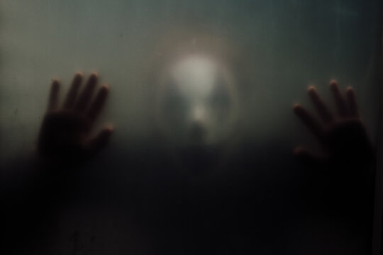 Terrifying clown pressed up against a foggy window looking in