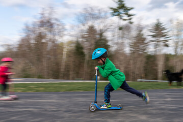 Boy riding a blue scooter on a road with motion blur effect.