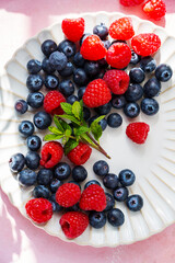 Closeup berries: strawberries, raspberries, blueberries in a plate