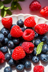 Closeup berries: strawberries, raspberries, blueberries in a plate