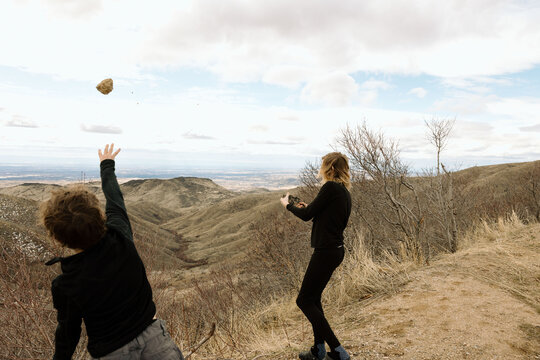Boys hurl rocks into canyon under wide sky