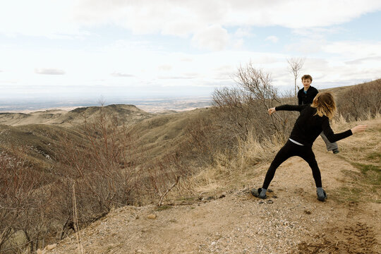 Two teen boys throwing rocks on dry mountain ridge