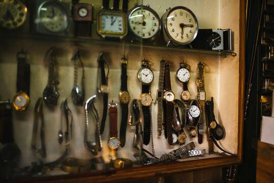 Watchmaker displaying wristwatches and clocks in workshop - Powered by Adobe