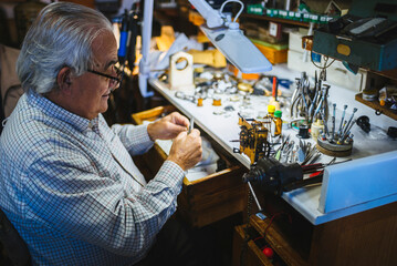 Senior watchmaker repairing clock mechanism in workshop