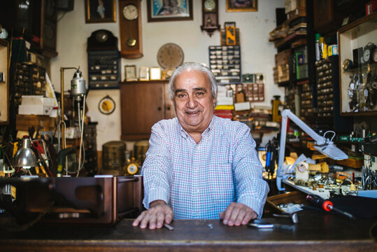 Senior watchmaker smiling in his authentic workshop