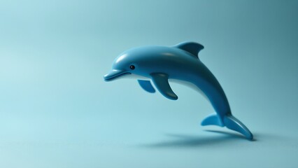 Fototapeta premium Creative composition of toy dolphin placed on blue surface for ocean concept in studio