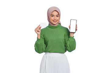 Cheerful beautiful Asian woman in green sweater and hijab showing blank screen mobile phone, holding credit card isolated on transparent background