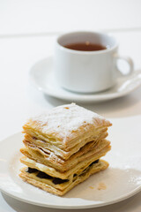 mille feuille layered pastry with chocolate filling and a cup of tea behind