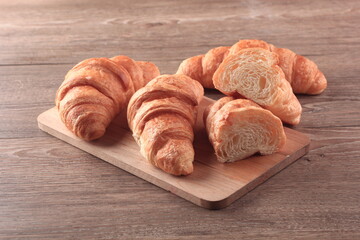 four croissant, one sliced, on a wooden cutting board