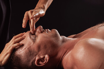 Naklejka premium Facial massage with finger pressure on brow ridge for relaxation and muscle tension relief.