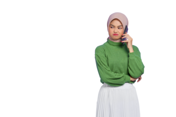 Annoyed beautiful Asian woman in green sweater and hijab talking on a mobile phone while looking aside isolated on transparent background