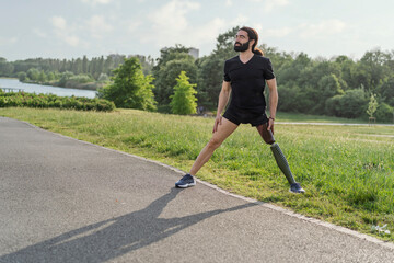 Athlete with prosthetic leg stretching outdoors before workout, resilience and adaptation