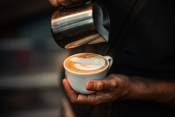 barista hand pouring milk for making latte art in cafe
