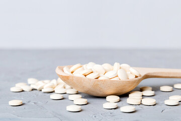 Heap of white pills on colored background. Tablets scattered on a table. Pile of red soft gelatin...