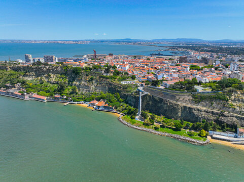 Riverside village and buildings below the Almada cliffs with a tall glass elevator connecting to the city above