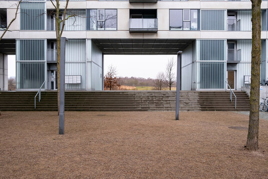 Modern housing complex with large central arch and soft grass area. Functional geometry and architectural openness define this urban design.