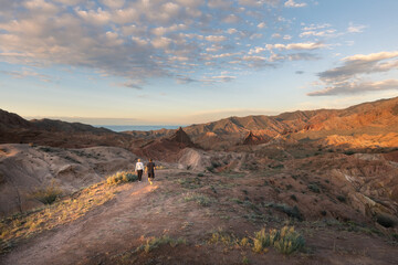 Two travelers hiking through Fairy Tale canyon in Kyrgyzstan during colorful sunset