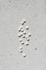 White vitamin pills on neutral concrete background with aesthetic sunlight shadow. Minimal beauty, wellness or pharmacy concept