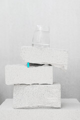 Minimal composition with stone blocks, glass of water and vitamin pill on a neutral background. Still life showing blocks of stone with a blue pill tucked into the gap between the two blocks