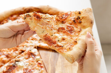 girl eating tasty delicious piece pizza with bacon, in cafe. woman holding with hand one slice.female biting delicious junk food.view from front and over the shoulder.advertising banner restaurants